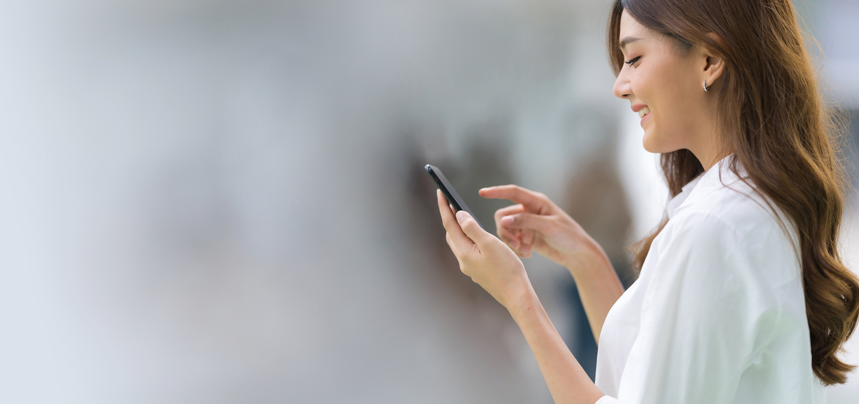 Outdoors Portrait of Happy Young Woman Using a Phone